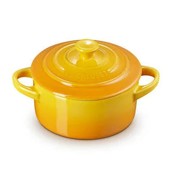 A small round enameled cast iron pot with lid, featuring a vibrant yellow-to-orange gradient glaze and double side handles, shown on a plain white background.
