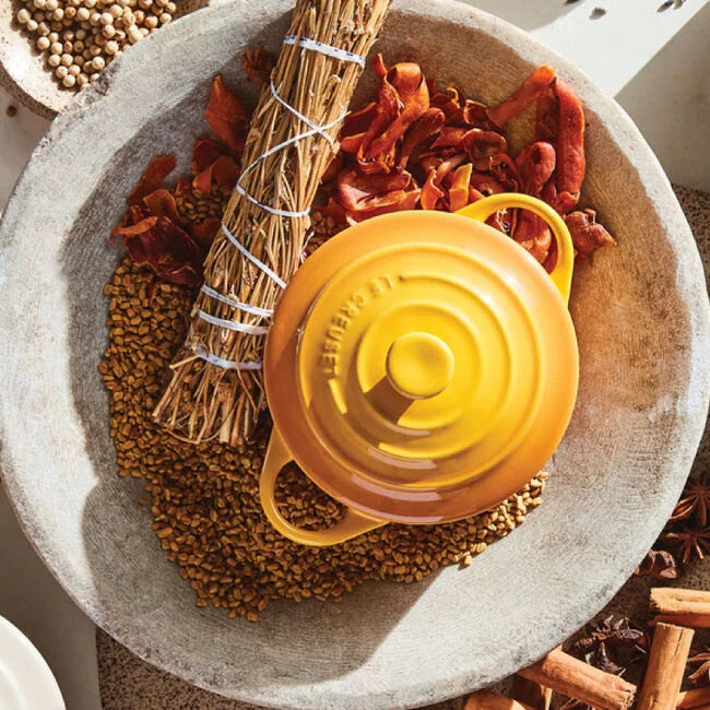 Yellow kitchen tool on a stone surface with dried herbs and spices
