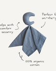 A moon-shaped plush attached to a soft muslin blanket, with text annotations reading "Helps with comfort + security," "Perfect for on-the-go," and "100% organic cotton." The graphic highlights the product's softness and portability.