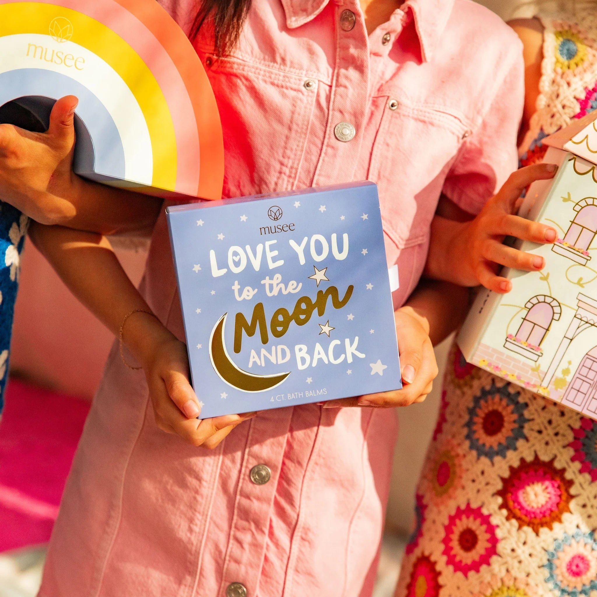Children holding a 'Love You to the Moon and Back' book with colorful backgrounds