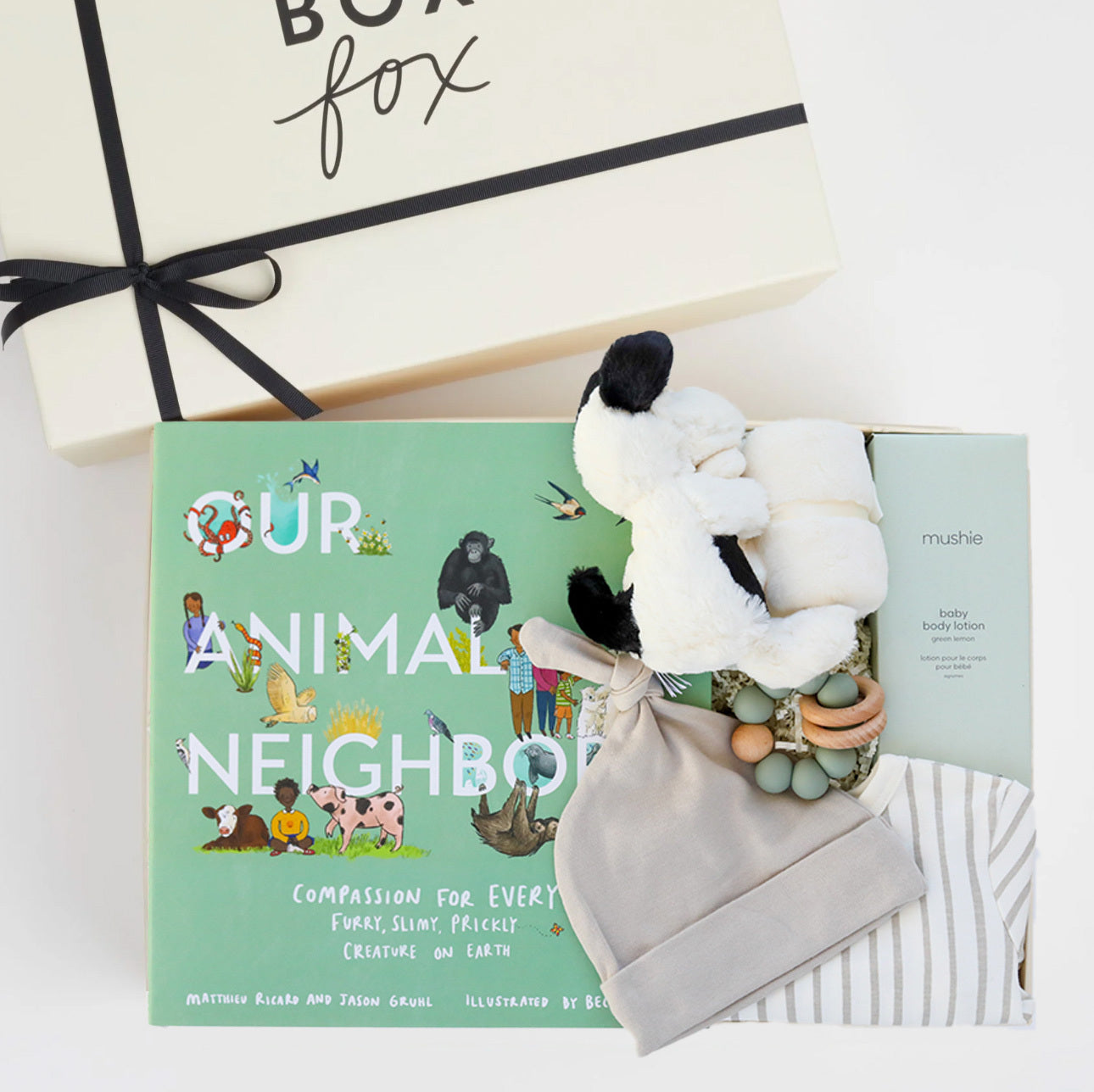 BOXFOX Original creme New Family Gift Box packed with PEHR cozy grey striped onesie 3-6 months, Jellycat puppy lovey, Our Animal Neighbors book, Pipette baby oil, Alva sage green teether, and Alva sage green beanie