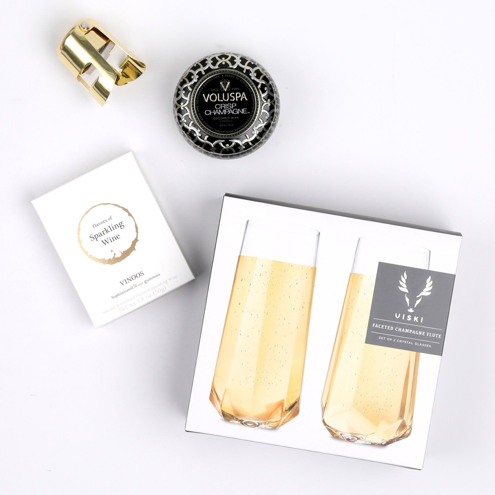 Faceted stemless champagne flutes, sparkling wine gummies, crisp champagne tin candle and gold champagne stopper
