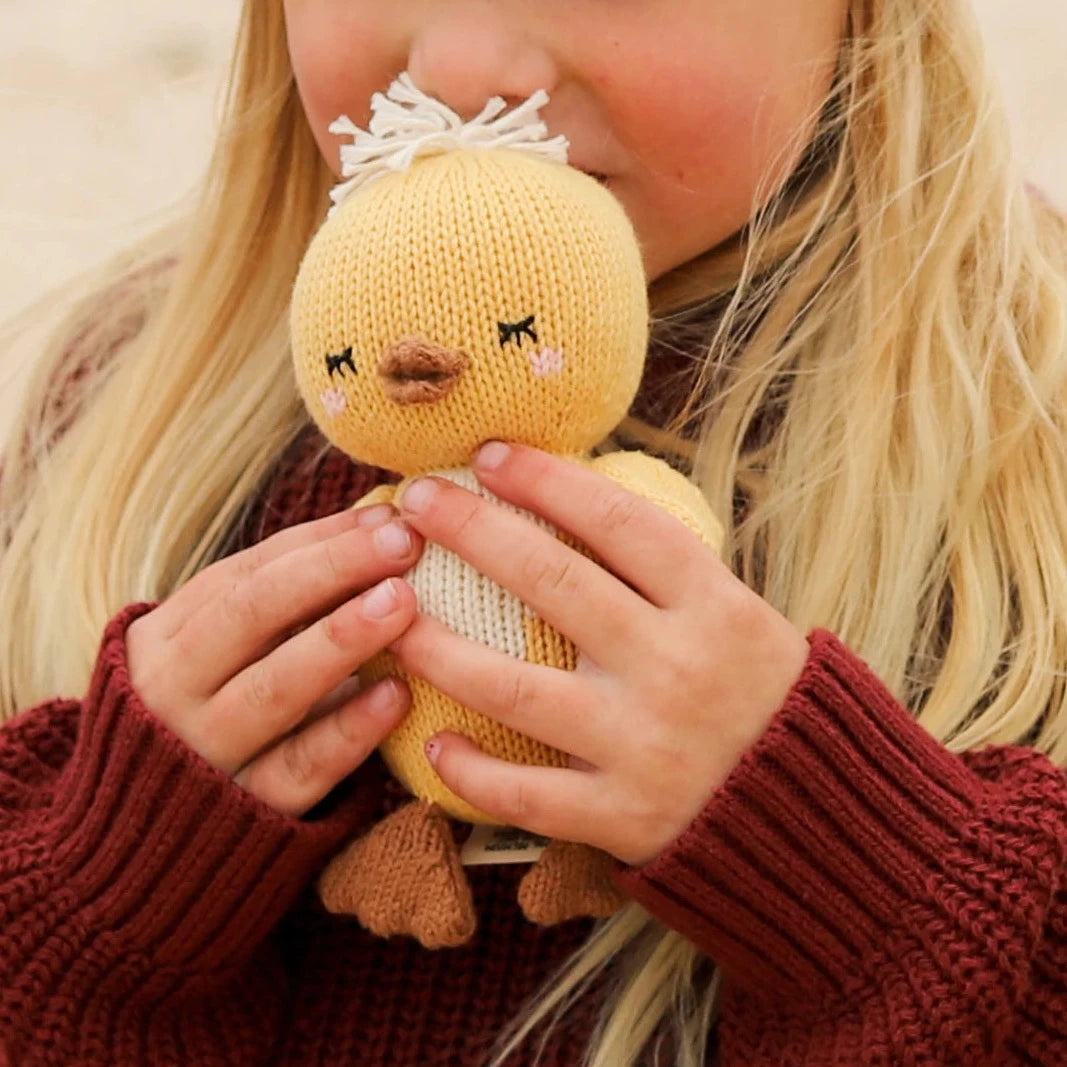 girl with blonde hair holding yellow stuffed baby duck
