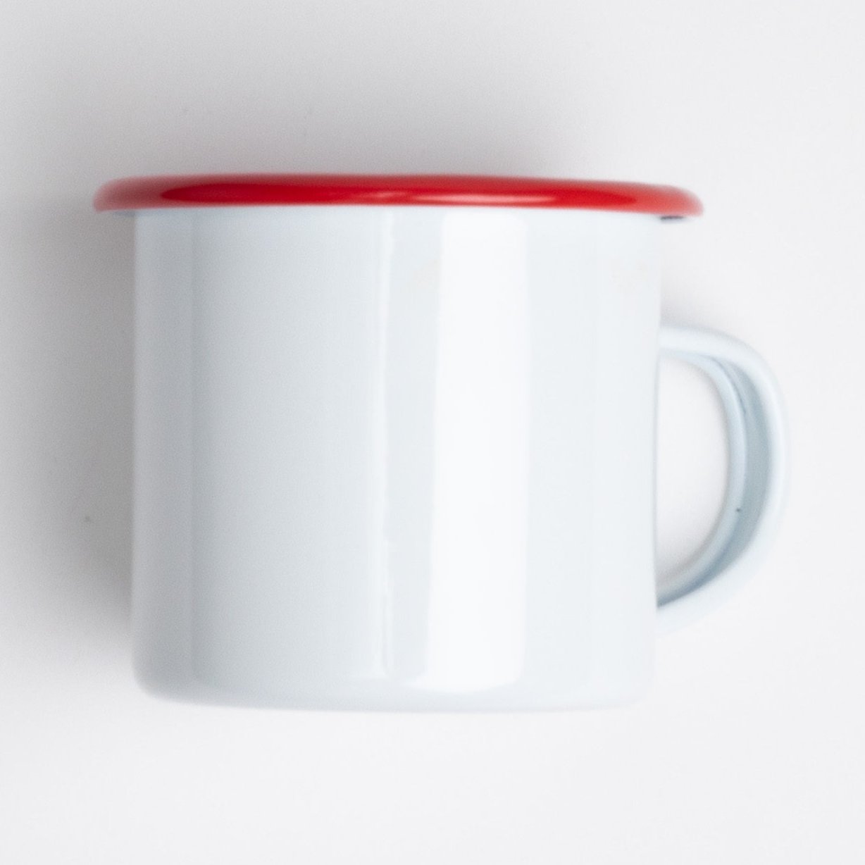 light-colored enamel mug with a red rim. This classic style is often associated with camping or outdoor themes due to its durability. 