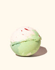 White and green bath bomb with specks of red throughout it. Bottom half of the bath bomb is green