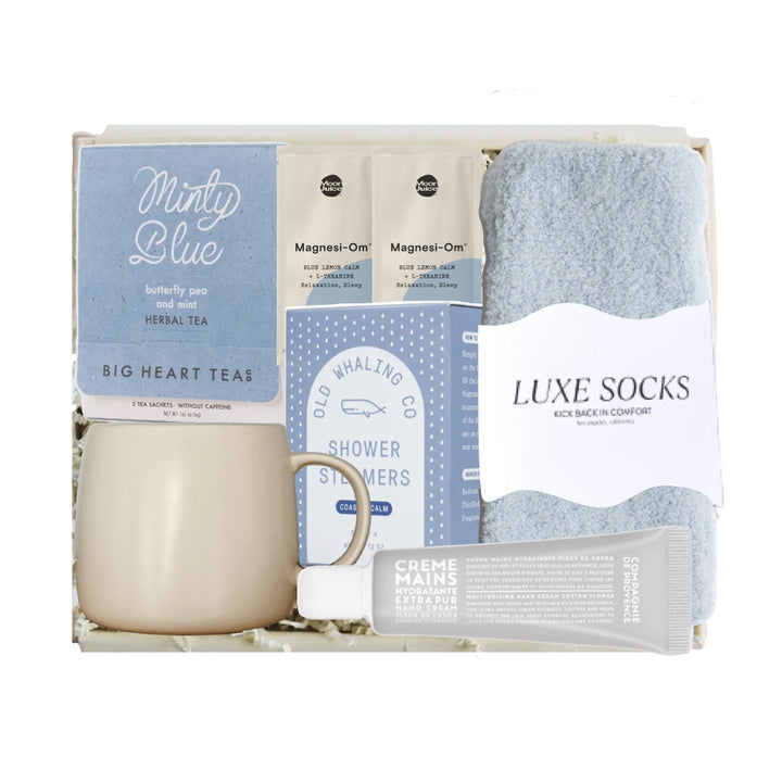 Gift set with mug, tea, shower steamers, and socks on a white background