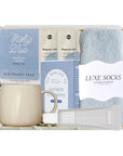 Gift set with mug, tea, shower steamers, and socks on a white background