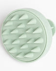 sage green scalp massager against a white background