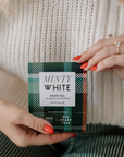 Person holding a box of 'Minty White' white tea with a plaid pattern.