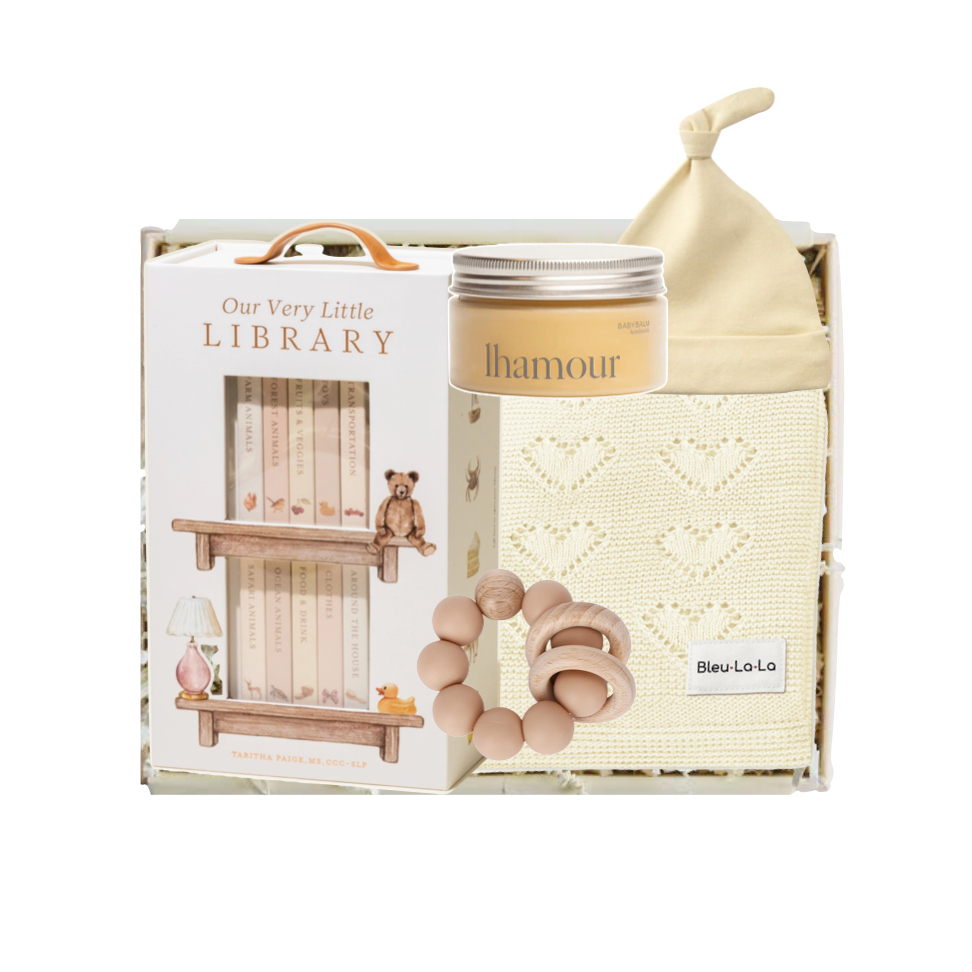 Baby product set with 'Our Very Little Library' packaging, including a bottle, bib, and rattle.