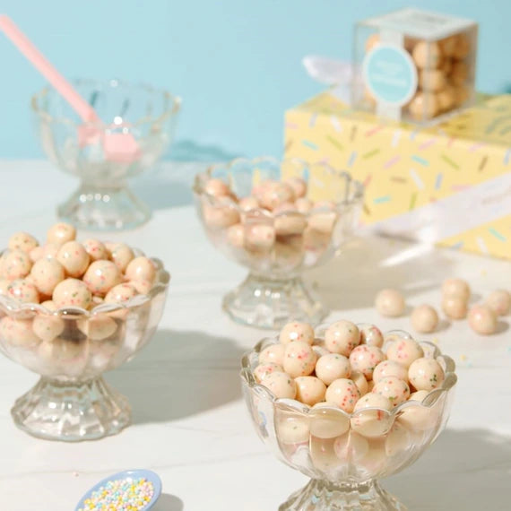 white chocolate balls with colorful sprinkles in them inside clear glass dishes