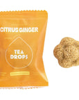 bright yellow tea drop packaging with white text. compressed tea flower next to it