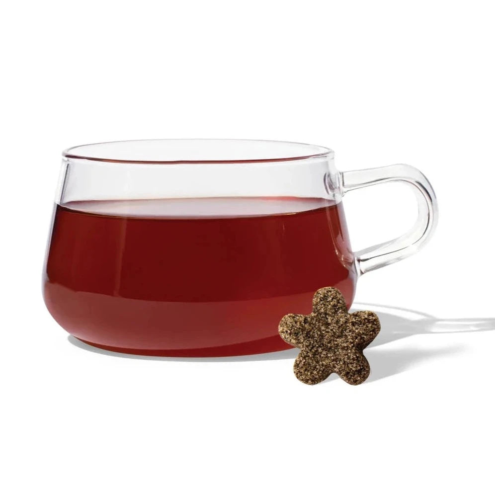 clear glass mug with purple tea inside. infant of the mug is a star comprised tea drop