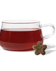 clear glass mug with purple tea inside. infant of the mug is a star comprised tea drop