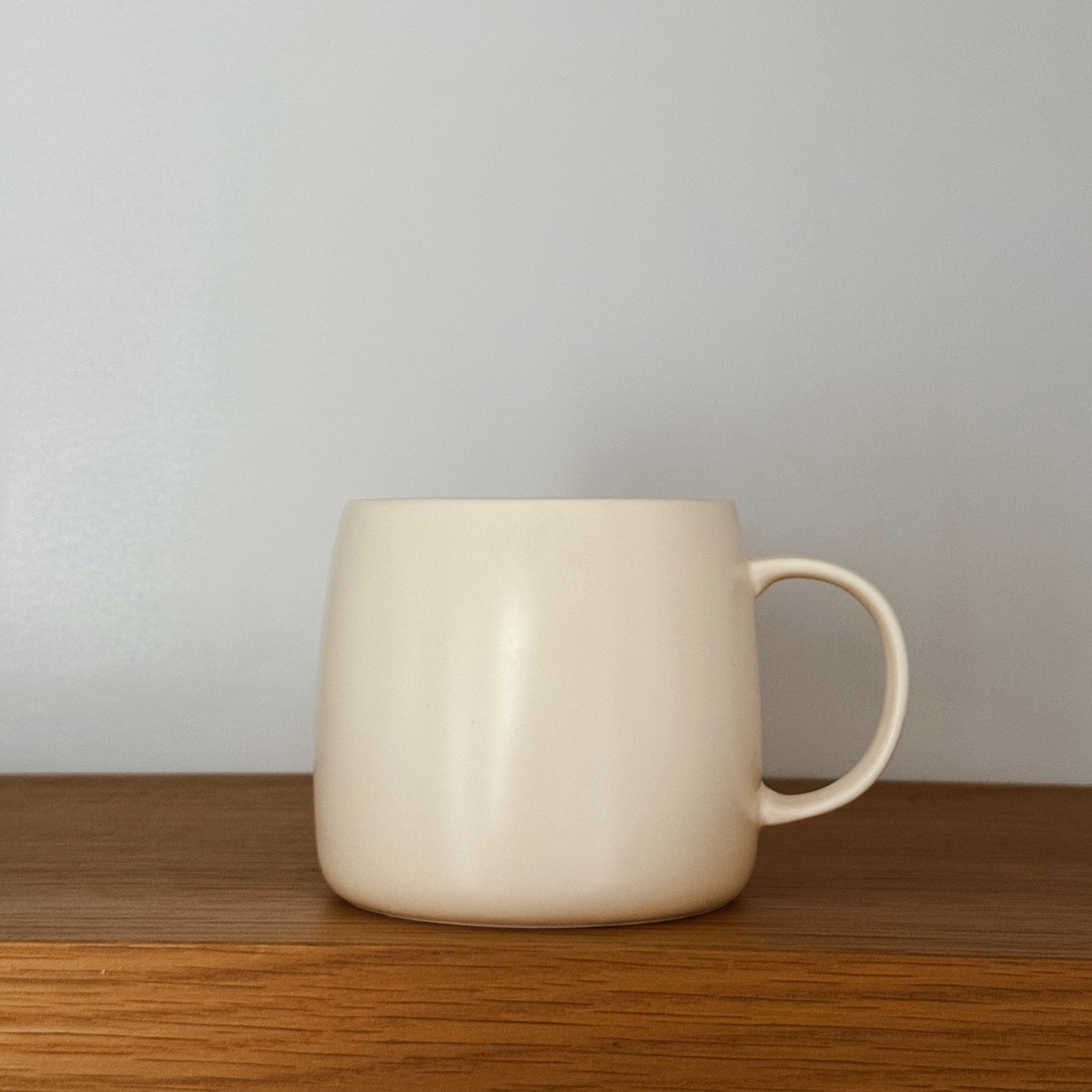 White ceramic mug on a wooden surface with a plain background