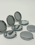 silver compact mirrors lined up next to each other, some opened, some closed