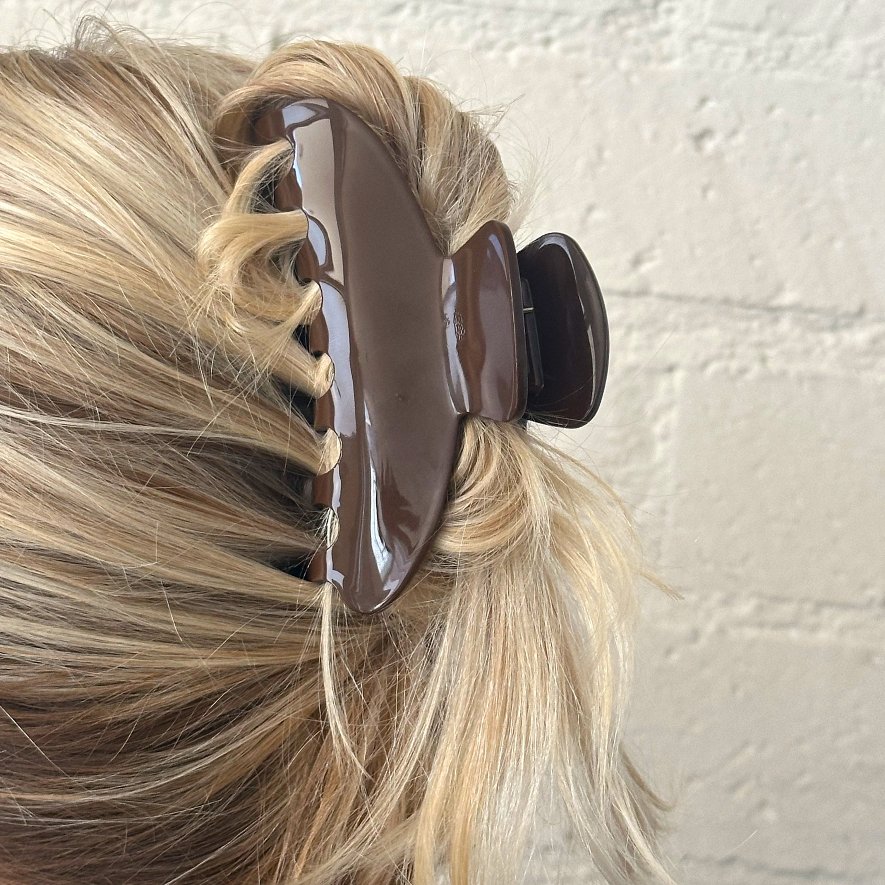 Brown hair clip holding blonde hair against a light background