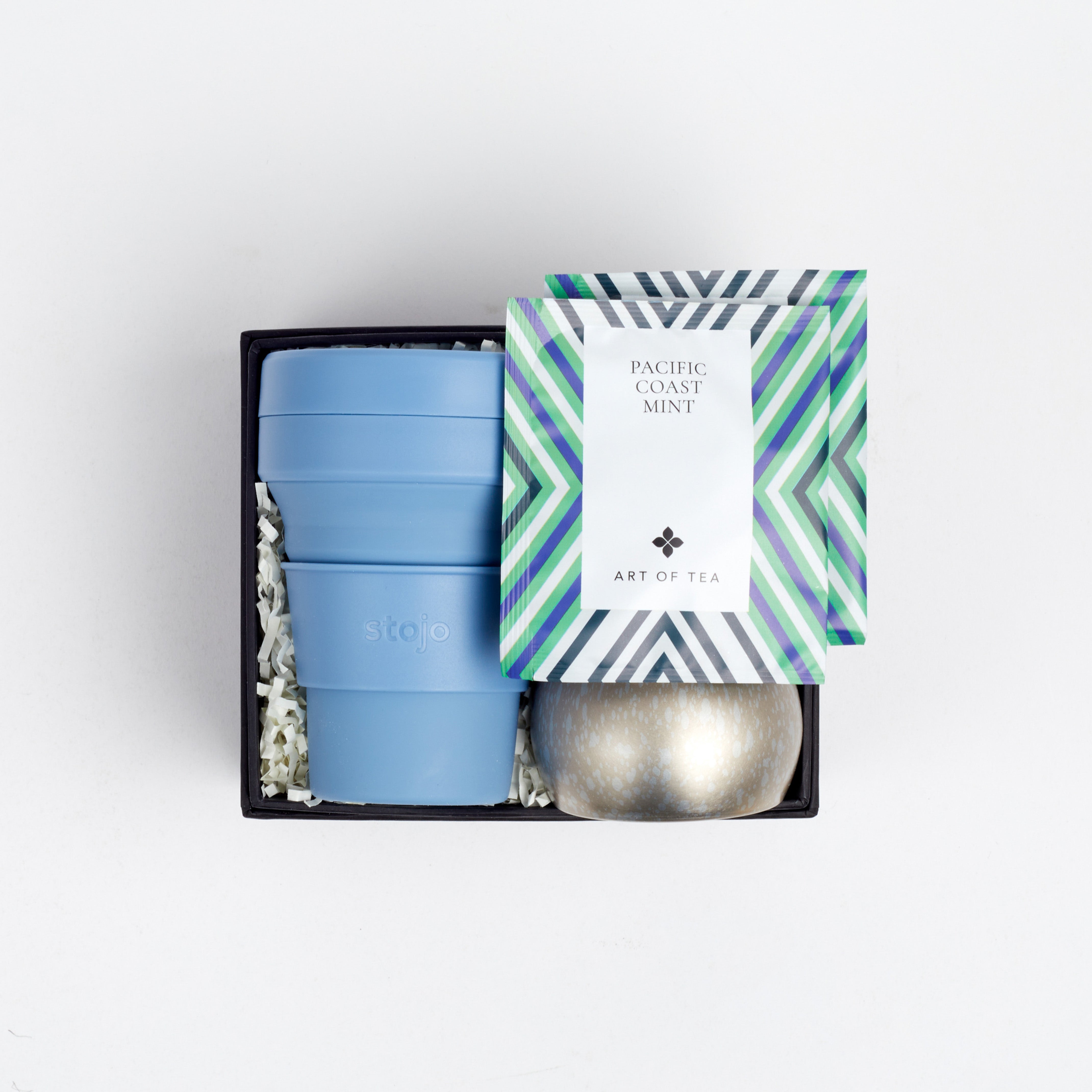 Open BOXFOX box with cup, candle and tea sachets, on white background.