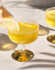 Gatsby Coupe Glasses filled with yellow liquid and lemon wedges