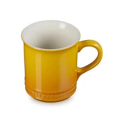 A Le Creuset Le High Life mug in a vibrant yellow color with a glossy finish and a contrasting white interior, shown on a plain white background.