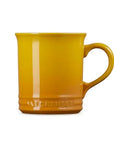 A yellow Le Creuset ceramic mug with a handle, shown on a plain white background.