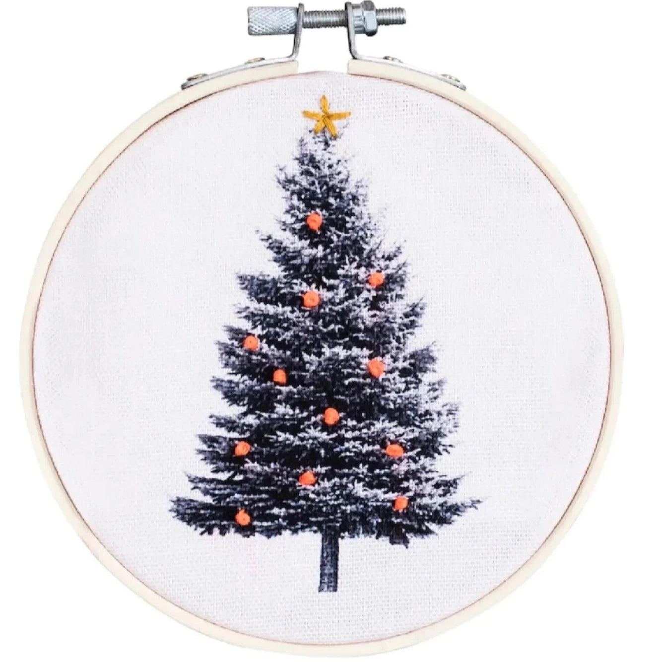 white fabric with black Christmas tree printed on it. Embroidered onto the tree are orange ornaments and a gold star tree topper. Embroidery hoop is light brown with silver metal clasp