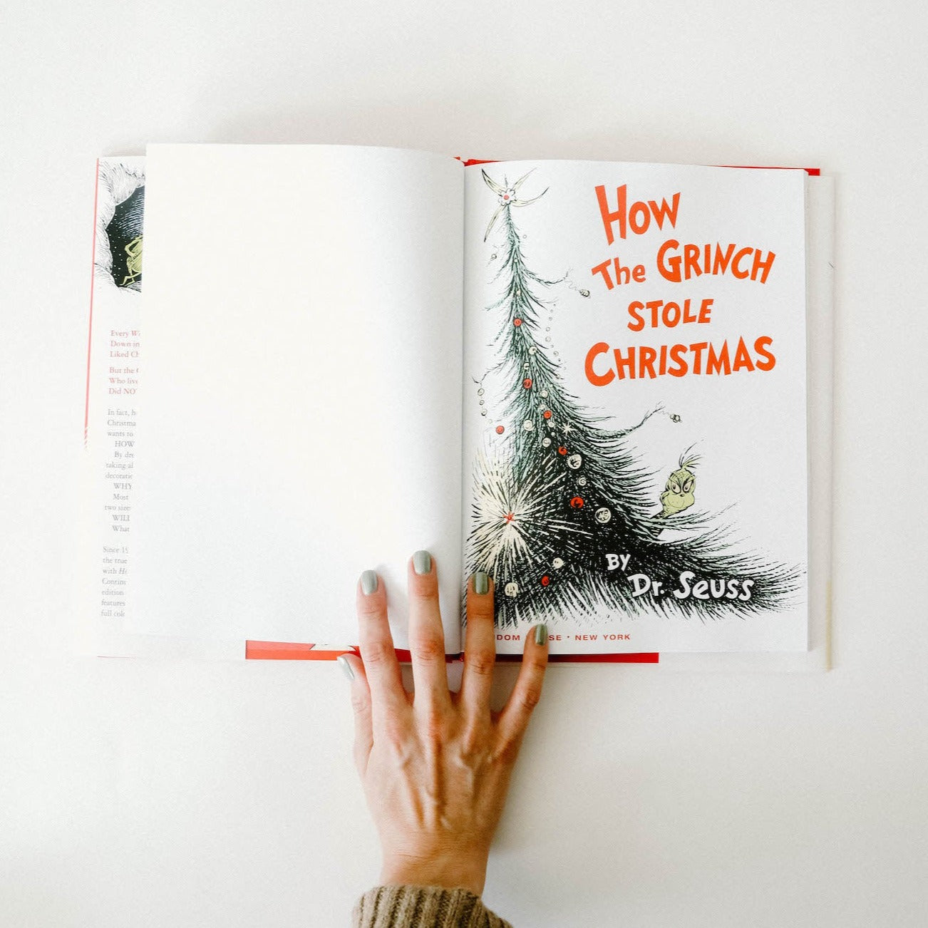 "How the Grinch Stole Christmas" opened up to the cover page, which is white on the left and has a cartoon Christmas tree and the title of the book in red on the right.