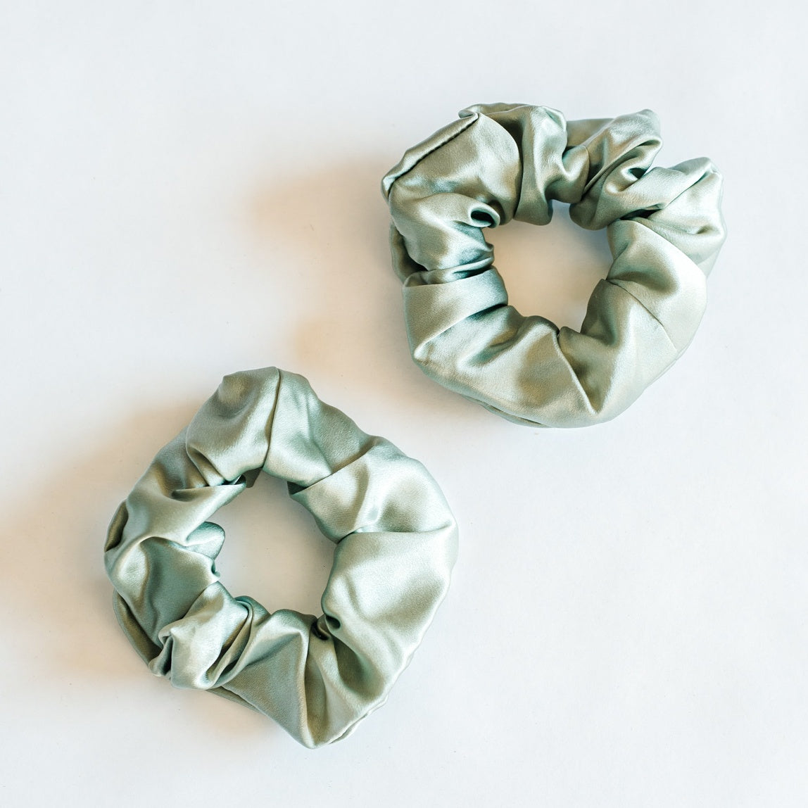 Two thick sage green srunchies.
