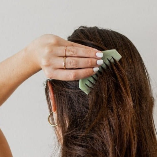 girl combing brown hair with green scalp jade Gua Sha