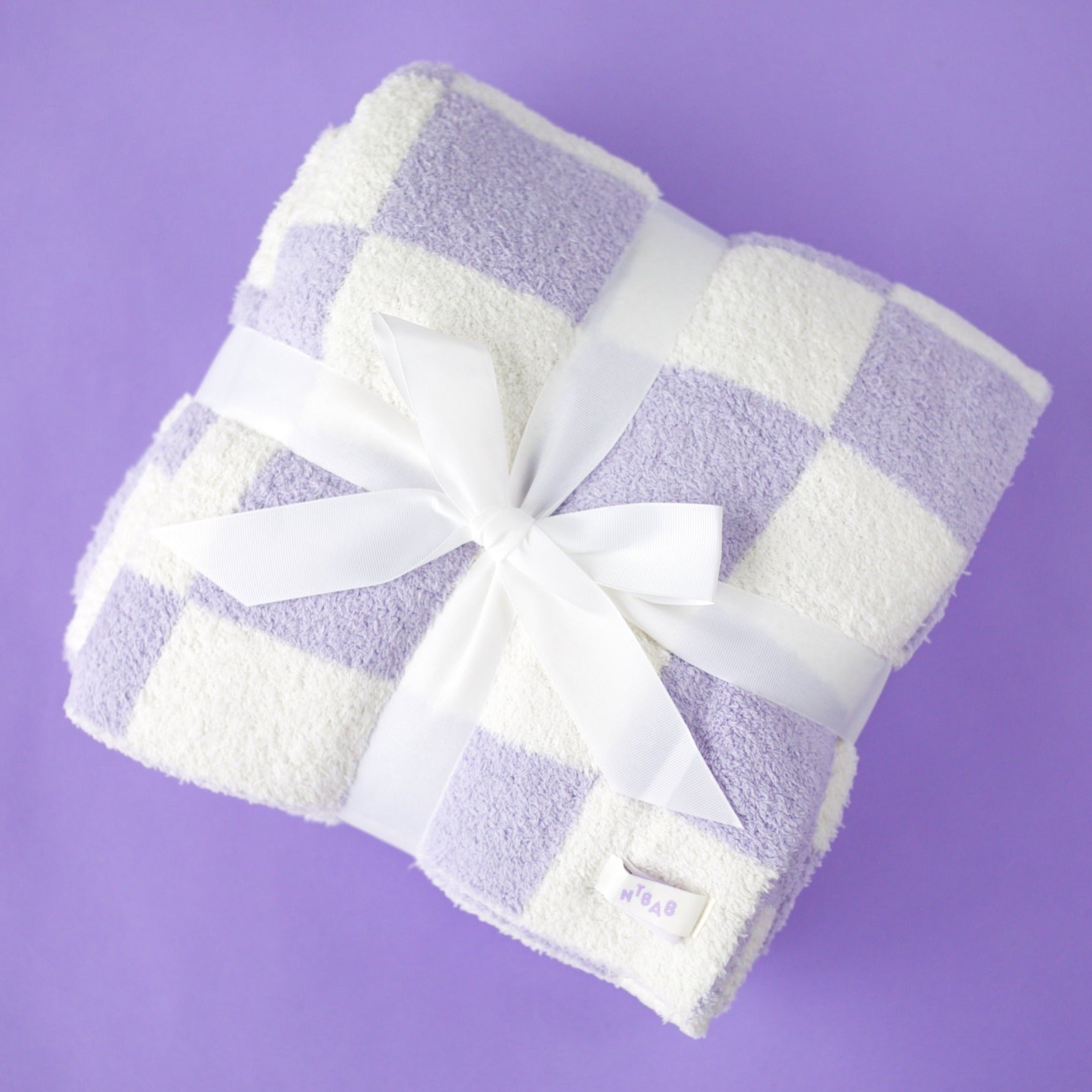 A lavender and white checkered blanket against a purple background