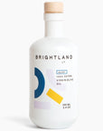 A white bottle with blue, yellow and grey geometric motifs and the following in black writing, "BRIGHTLAND CA ALIVE 100% EXTRA VIRGIN OLIVE OIL 100ML 3.4 OZ" photographed on white background.