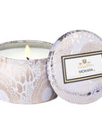 Mokara candle in silver tin with floral detail, with lid leaning against it.