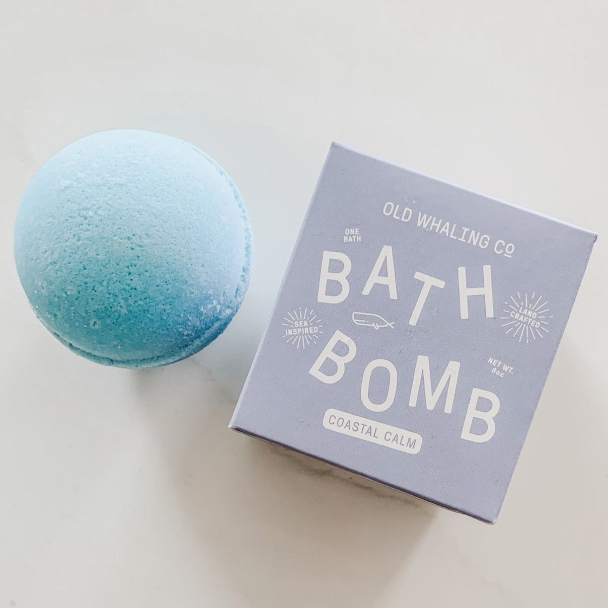 Blue bath bomb next to blue box with white text.