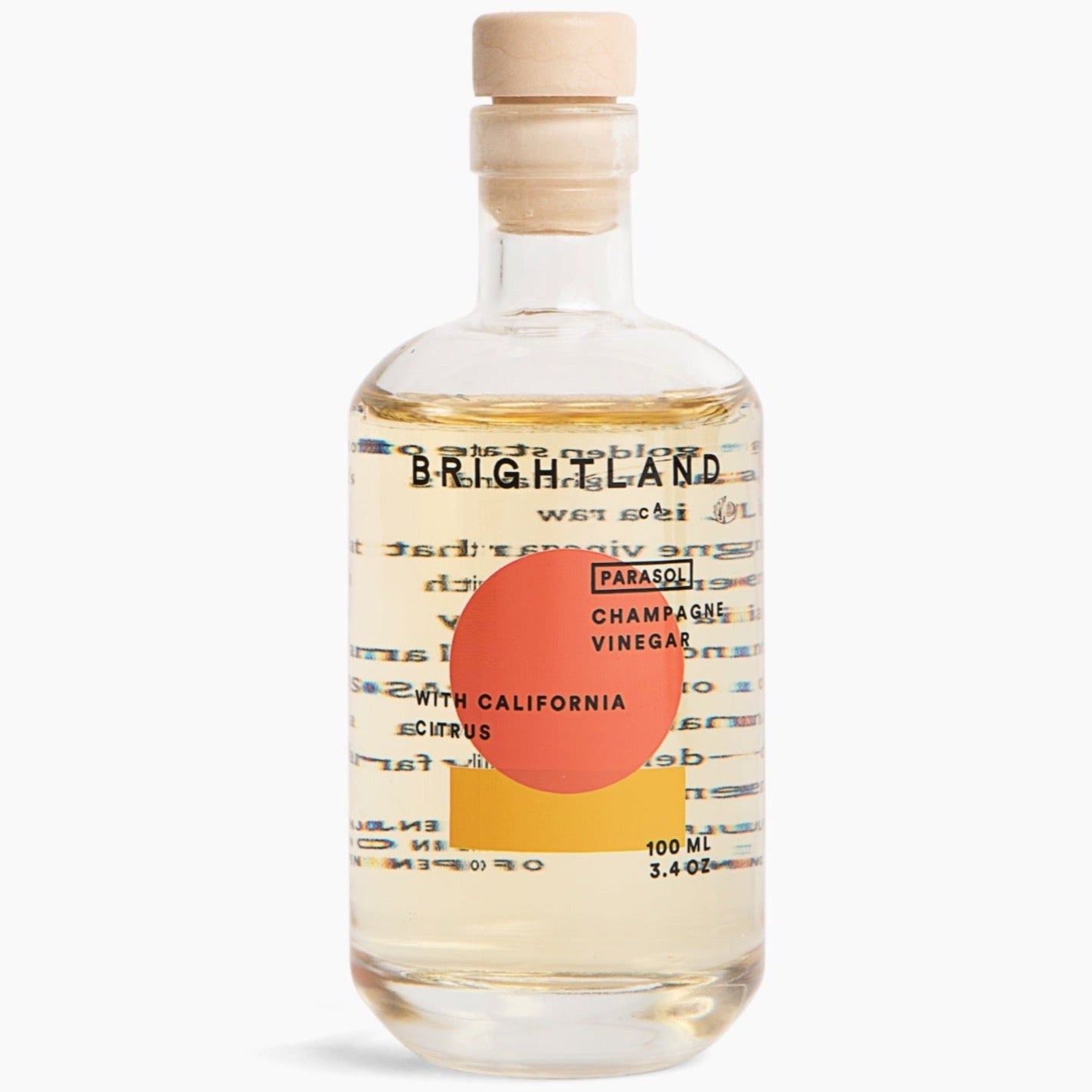 A clear glass bottle with orange and yellow geometric motifs with the following in black writing "BRIGHTLAND CA PARASOL CHAMPAGNE VINEGAR WITH CALIFORNIA CITRUS 100ML 3.4 OZ" photographed on white background.