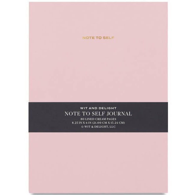 Pink notebook with "Note to Self" written in gold foil across the top. Dark band is wrapped across notebook.