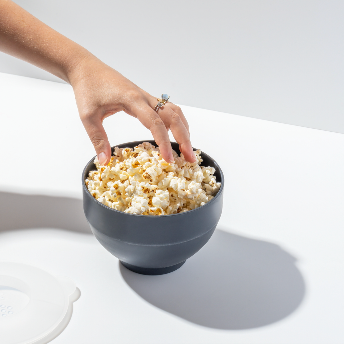 Hand reaching into black W&P popcorn bowl