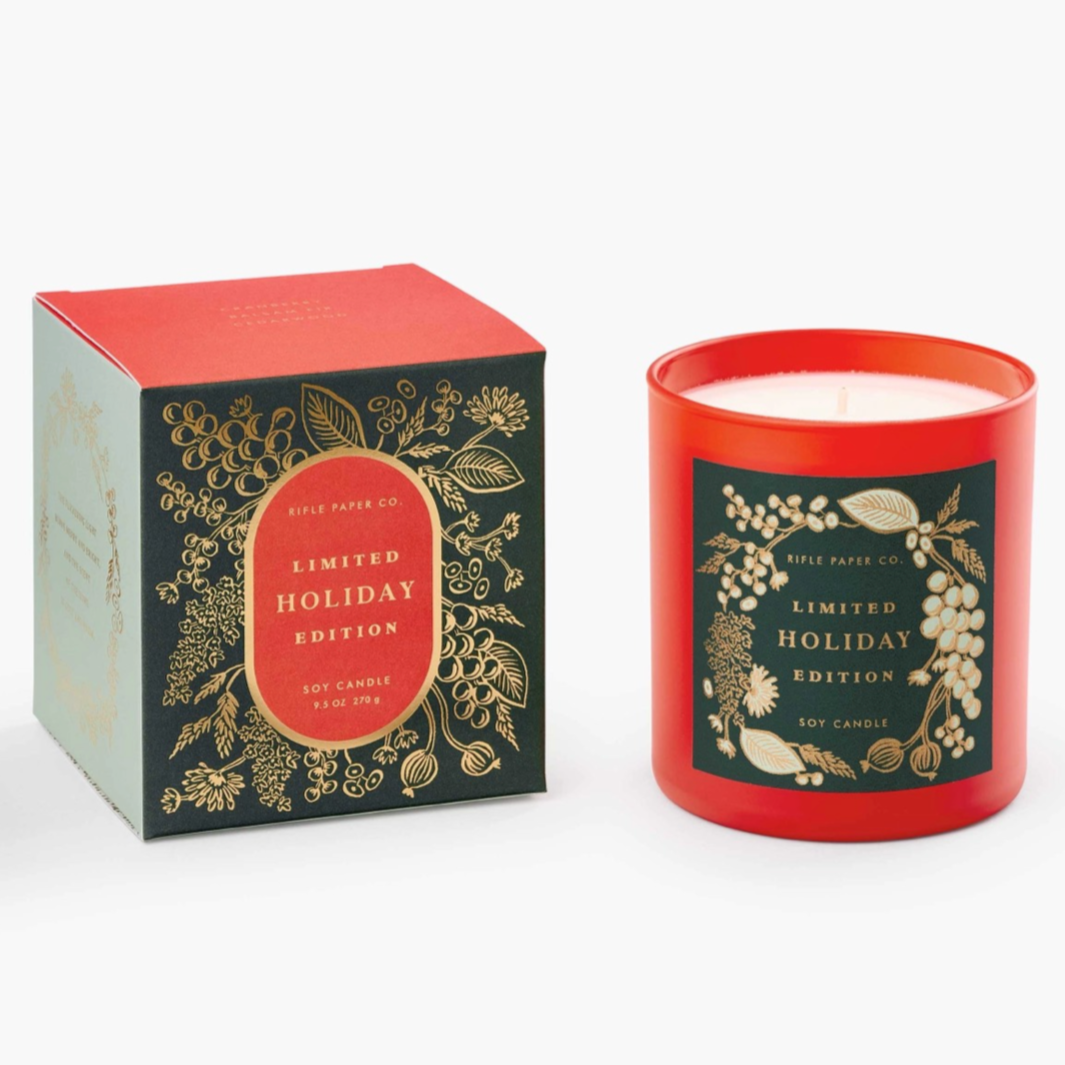 red glass container with green label. box for candle is green with a red top. the box has gold accents and text around it