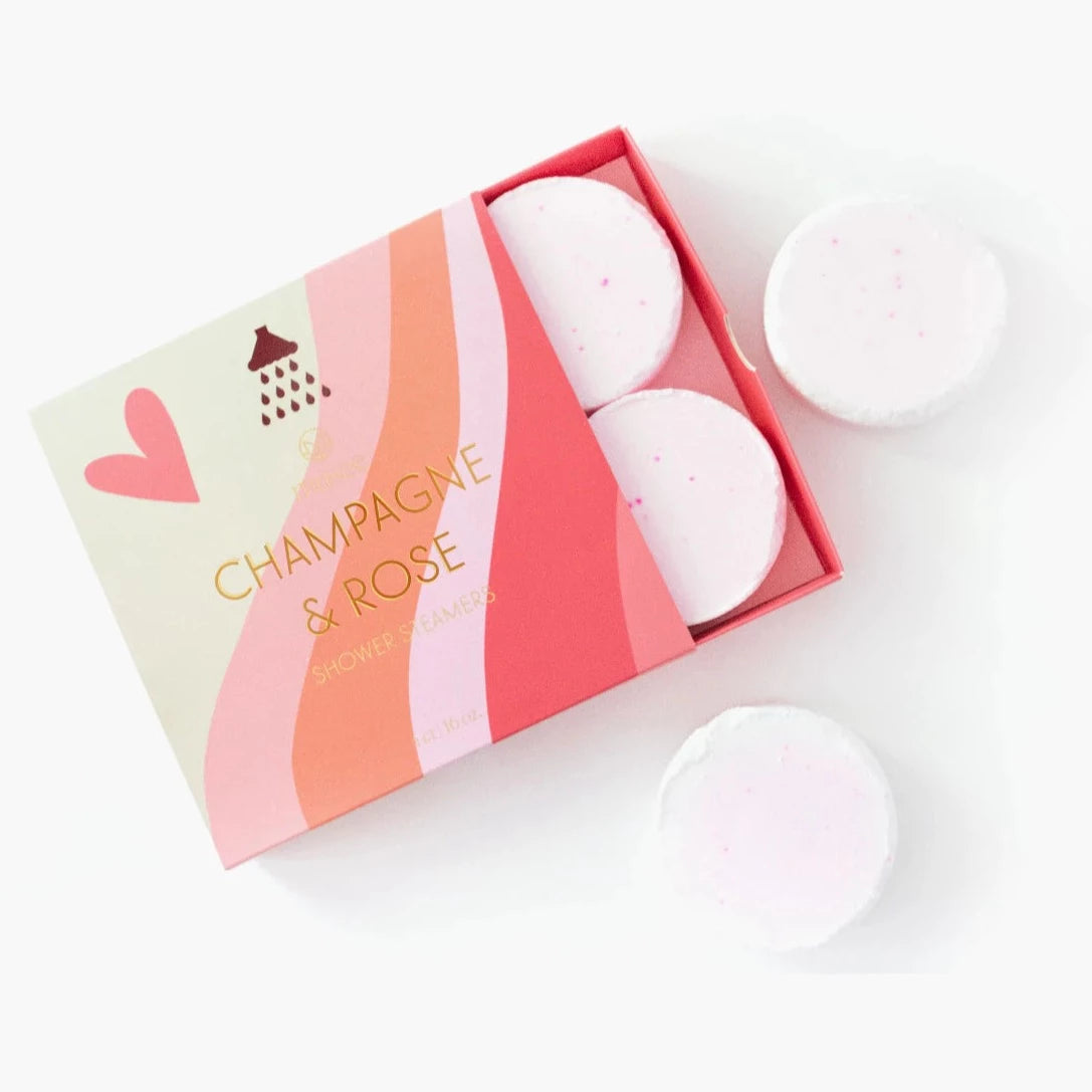 light pink champagne and rose shower steamers. packaging is a box with a. pink heart on the left hand side and waves of color ranging from cream, pink, orange, and red
