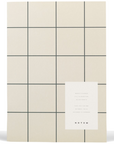Cream colored notebook with gray grid detail.