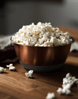 bowl of popped popcorn sitting on a wooden table