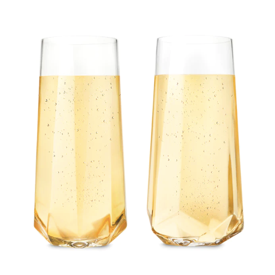 Two clear, stemless champagne flutes filled with bubbly champagne photographed on white background