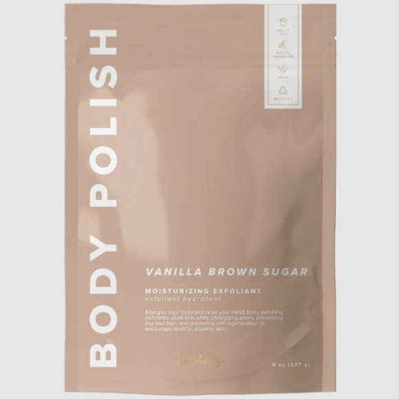 Rectangular, sealed, mauve package with white lettering that reads "BODY POLISH" on side and "VANILLA BROWN SUGAR MOISTURIZING EXFOLIANT" on bottom right. Photographed on grey background. 