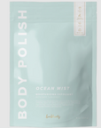 Rectangular, sealed, light blue plastic bag with white text that reads "BODY POLISH" on the side and "OCEAN MIST MOISTURIZING EXFOLIANT" in bottom right. Photographed on grey background. 