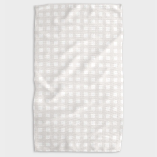 A white tea towel with beige grid design folded into a rectangle and photographed on white background.