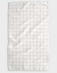 A white tea towel with beige grid design folded into a rectangle and photographed on white background.