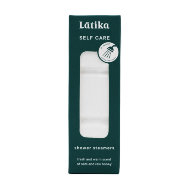 A tall rectangular dark teal box with clear window in middle showing stack of white shower steamers. White text on packaging reads, &quot;Latika Self Care Shower Steamers fresh and warm scent of oats and raw honey&quot;
