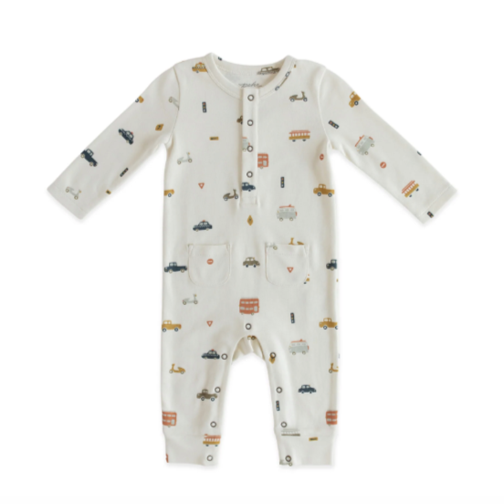 A white baby romper with multicolor car, bus and scooter print all over, metal snaps at collar and two pockets at hips. Photographed on white background.