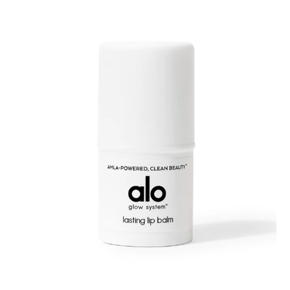 A small, white, cylindrical, plastic container with black text that reads, &quot; Amla-powered, clean beauty alo glow systems lasting lip balm&quot;. Photographed on white background.
