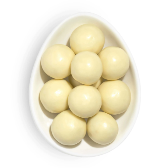 Several shiny, cream colored, candy balls resting in white egg-shaped dish photographed on white background.