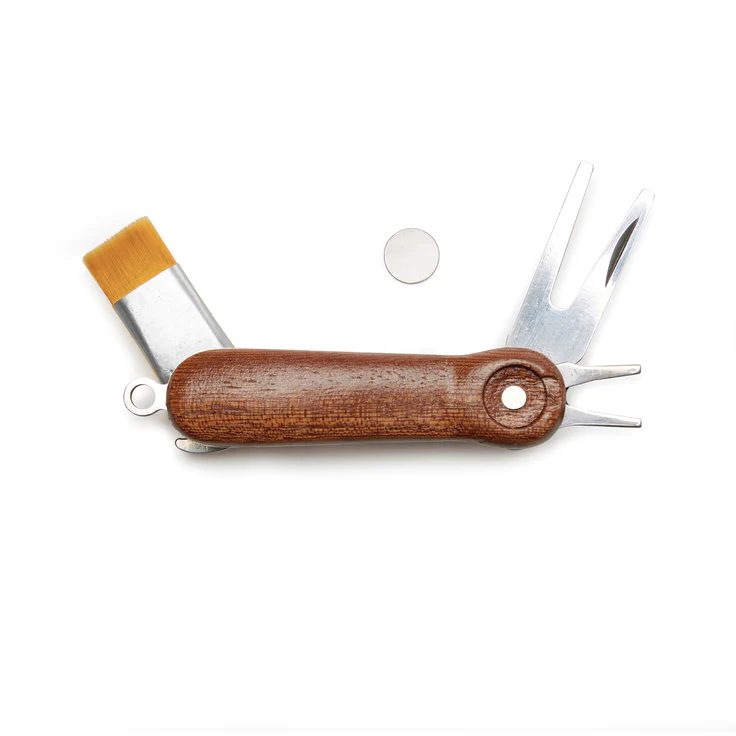 A multi-tool with dark wood body and stainless steel tools sticking out including: a magnetic ball marker, club and ball cleaning brush, divot tool, and shoe cleaning spike tool. Photographed on white background.